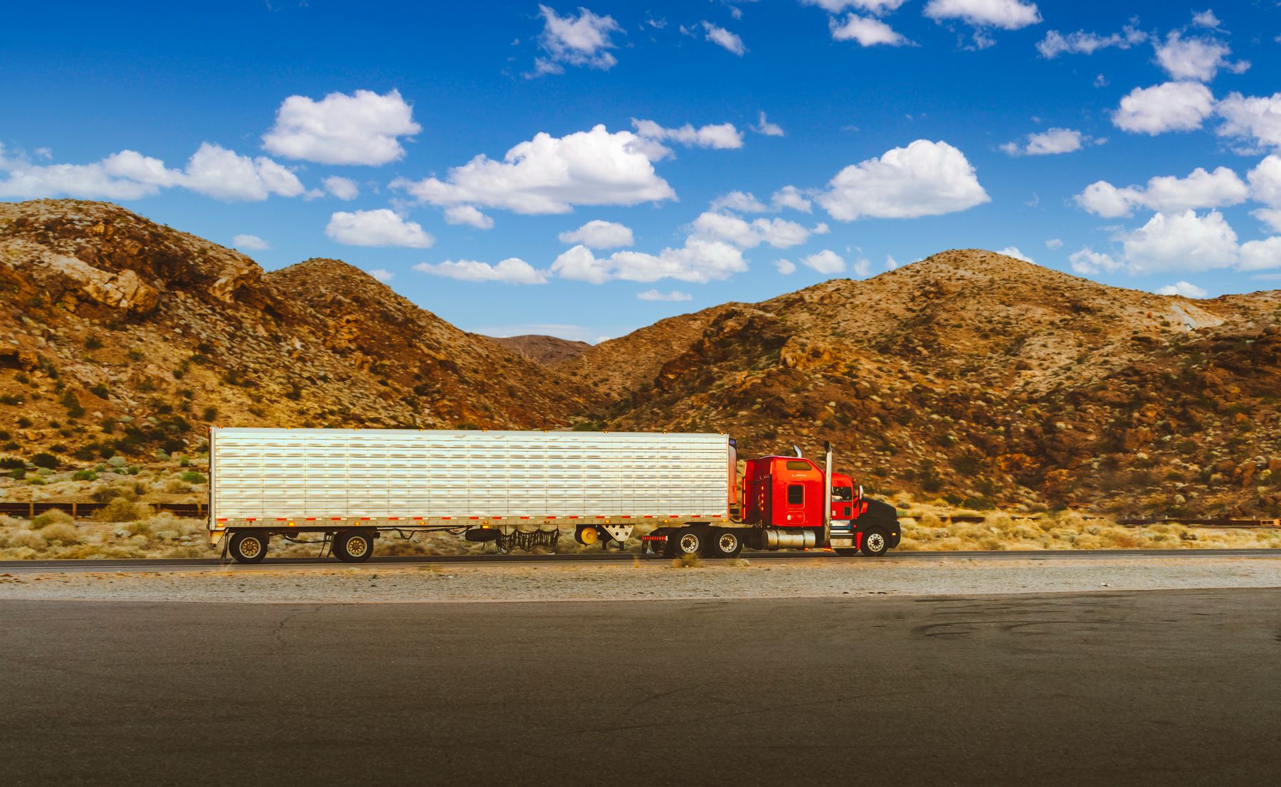 Semi-truck traveling through the Nevada desert with mountains in the distance